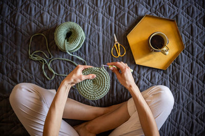 Low section of woman doing crocheting at home