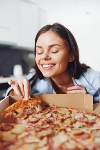 Portrait of young woman holding pizza