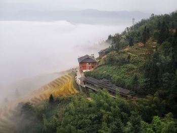 High angle view of house amidst trees and mountains against sky