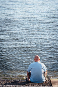 Rear view of man sitting at sea shore