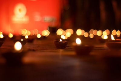 Close-up of illuminated diyas on floor at night