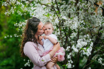Mother with daughter embracing by cherry tree