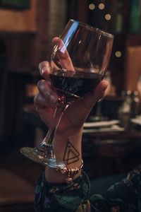 Cropped hand of woman holding red wine in darkroom