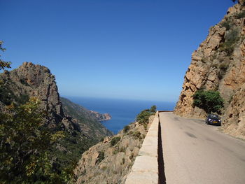 Road by mountain against clear blue sky