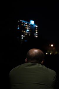 Rear view of man sitting at illuminated night