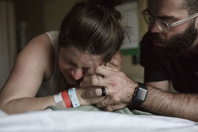 Close-up of man comforting painful pregnant woman on hospital bed