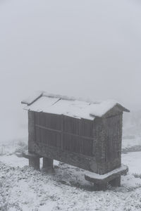 Built structure on snow covered field against sky