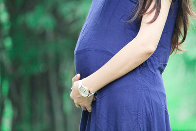 Midsection of woman with umbrella standing outdoors