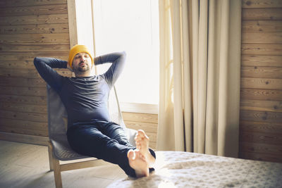 Side view of woman sitting on bed at home