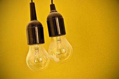 Close-up of yellow light bulb against wall