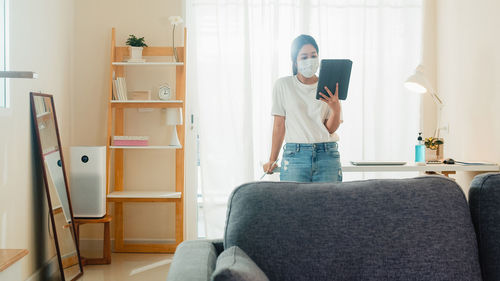 Full length of man using mobile phone at home