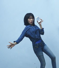 Portrait of young woman standing against white background