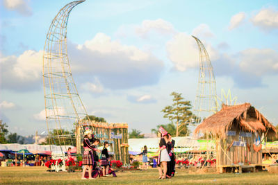 People at amusement park against sky