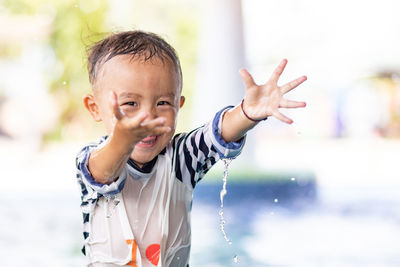 Portrait of cute boy with arms raised