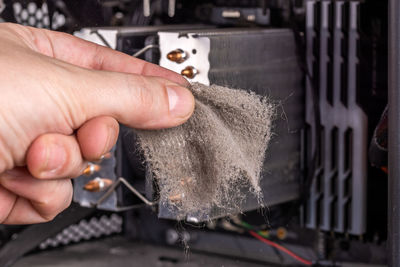 Bare caucasian hand holding dust clog in front of opened pc case during maintenance