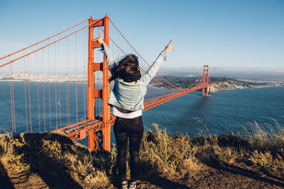 Rear view of woman standing against golden gate bridge