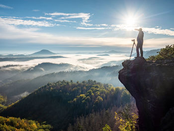 Photographer working in morning hills. nature landscape photographer with photo equipment on rock
