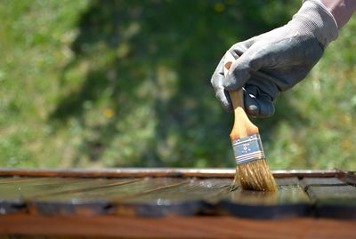 Close-up of man painting wood on field