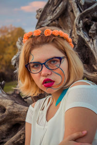 Portrait of young woman with face paint sitting outdoors