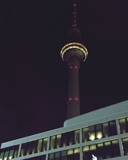 Low angle view of illuminated tower against sky at dusk