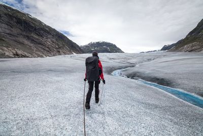 Full length of woman hiking on mountains against cloudy sky