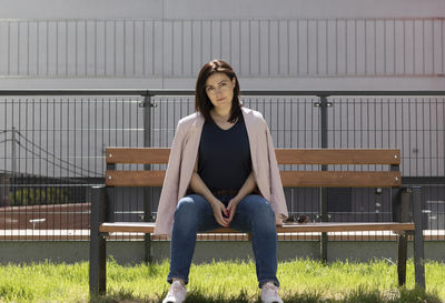 Beautiful brunette mature woman sitting on a bench in residential campus. confident female is