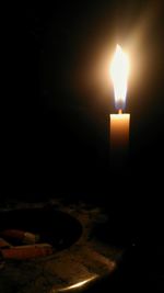 Close-up of lit candle in dark room