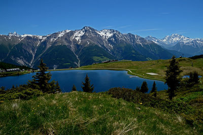 Scenic view of lake and mountains against blue sky