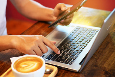 Midsection of woman holding coffee cup on table