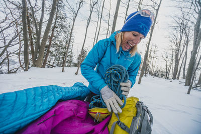 Happy female climber unpacking climbing rope from pack