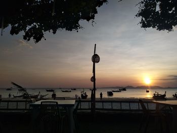 Silhouette street by sea against sky during sunset