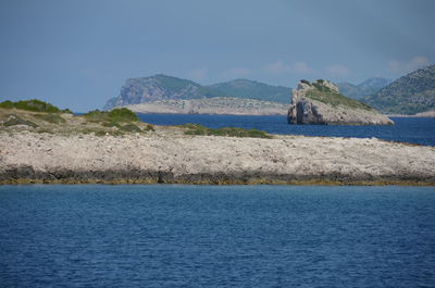 Scenic view of blue sea and mountain against sky