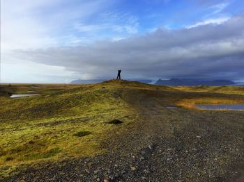 Man walking on landscape against sky