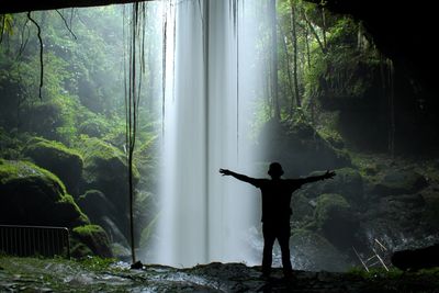 Silhouette of the man behind the waterfall