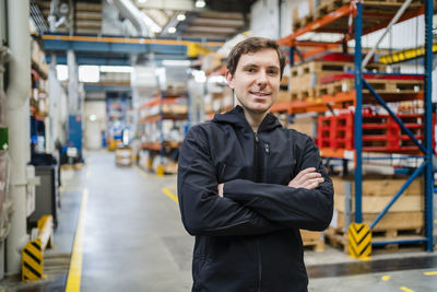 Confident employee standing in factory