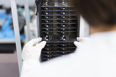 Female engineer inserting circuit board in machinery at factory