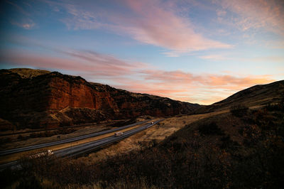 Road by mountains against sky during sunset