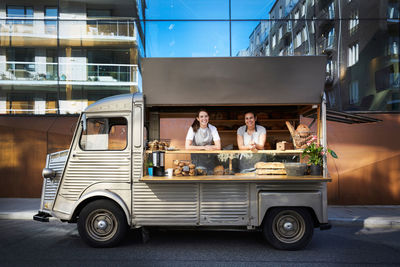 Portrait of female owners in food truck parked on city street against building