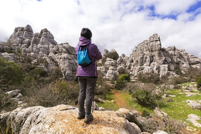 Rear view of woman standing on rock against sky