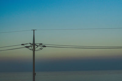 Low angle view of electricity pylon against clear sky