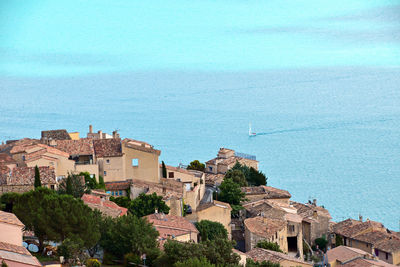 High angle view of townscape by sea against blue sky