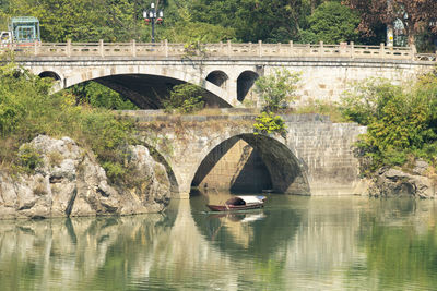 Arch bridge over river against trees