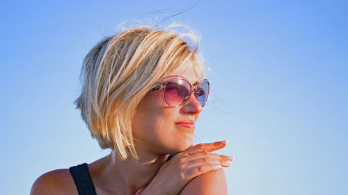 Portrait of young woman against clear blue sky