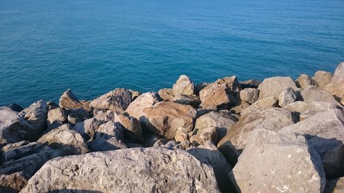 Rocks by sea against blue sky