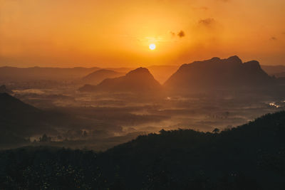 Scenic view of silhouette mountains against orange sky