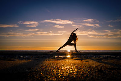 Silhouette woman on beach against sky during sunset