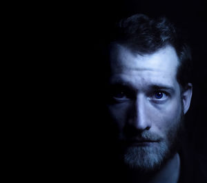 Close-up portrait of young man against black background