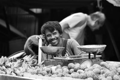 Smiling mature vendor looking away by fruit stall