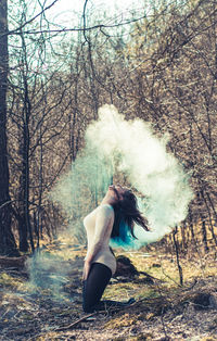 Woman standing by tree in forest