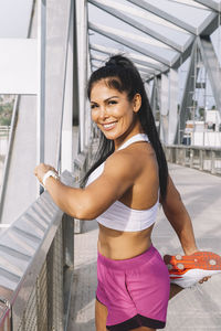 Attractive and happy middle-aged woman stretching her legs on a bridge outdoors